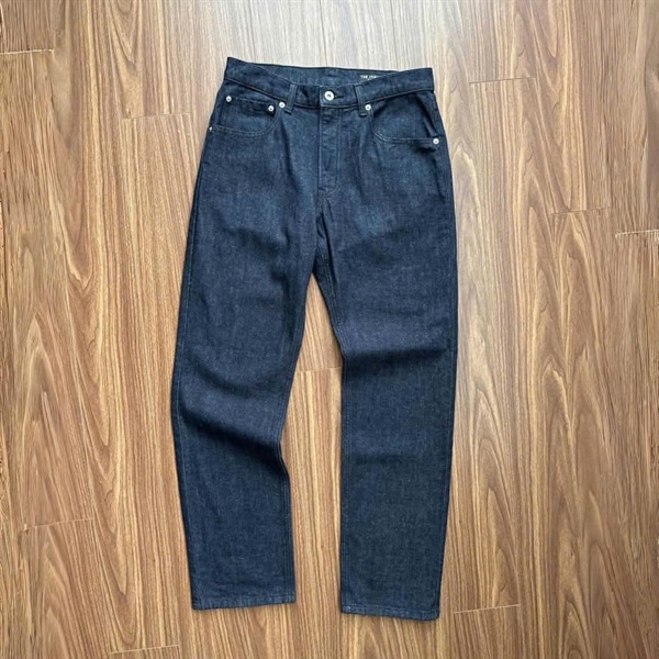 Dark indigo straight-leg jeans laid flat on a wooden floor, front view showing pockets and metal button
