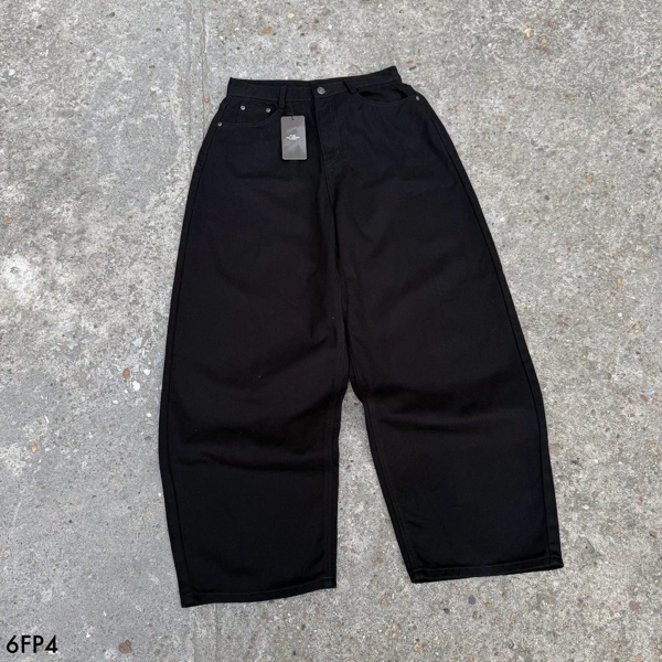 Ba chiếc quần jeans ống rộng màu đen trải phẳng trên nền xi măng, hai chiếc hai bên bị cắt khung