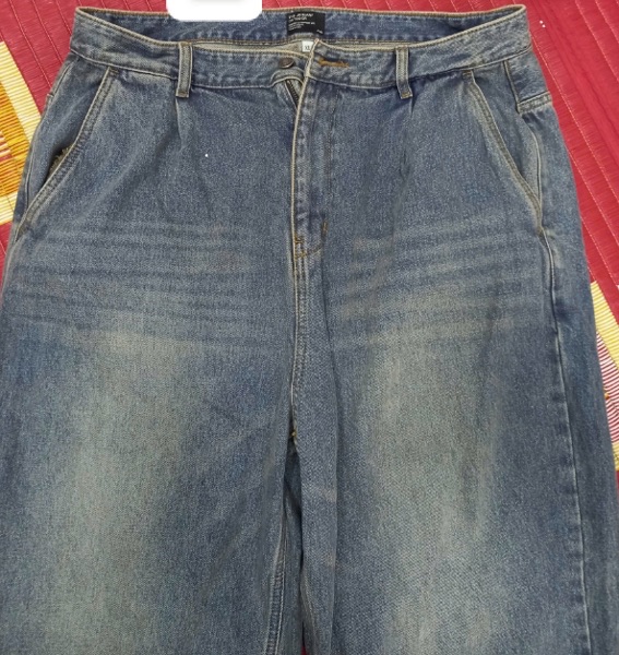 Quần jeans ống rộng màu xanh wash bạc, trải phẳng mặt trước, cận phần cạp, khoá và túi chéo hai bên