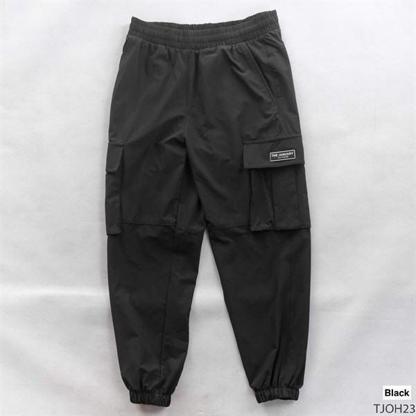 Quần jogger túi hộp màu đen trải phẳng mặt trước, cạp chun, bo gấu, nhãn chữ nhật trên nắp túi bên