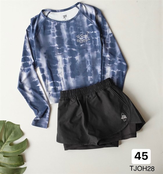 Flat lay of a women's swim set: navy and white tie-dye long-sleeve cropped top with black elastic-waist shorts
